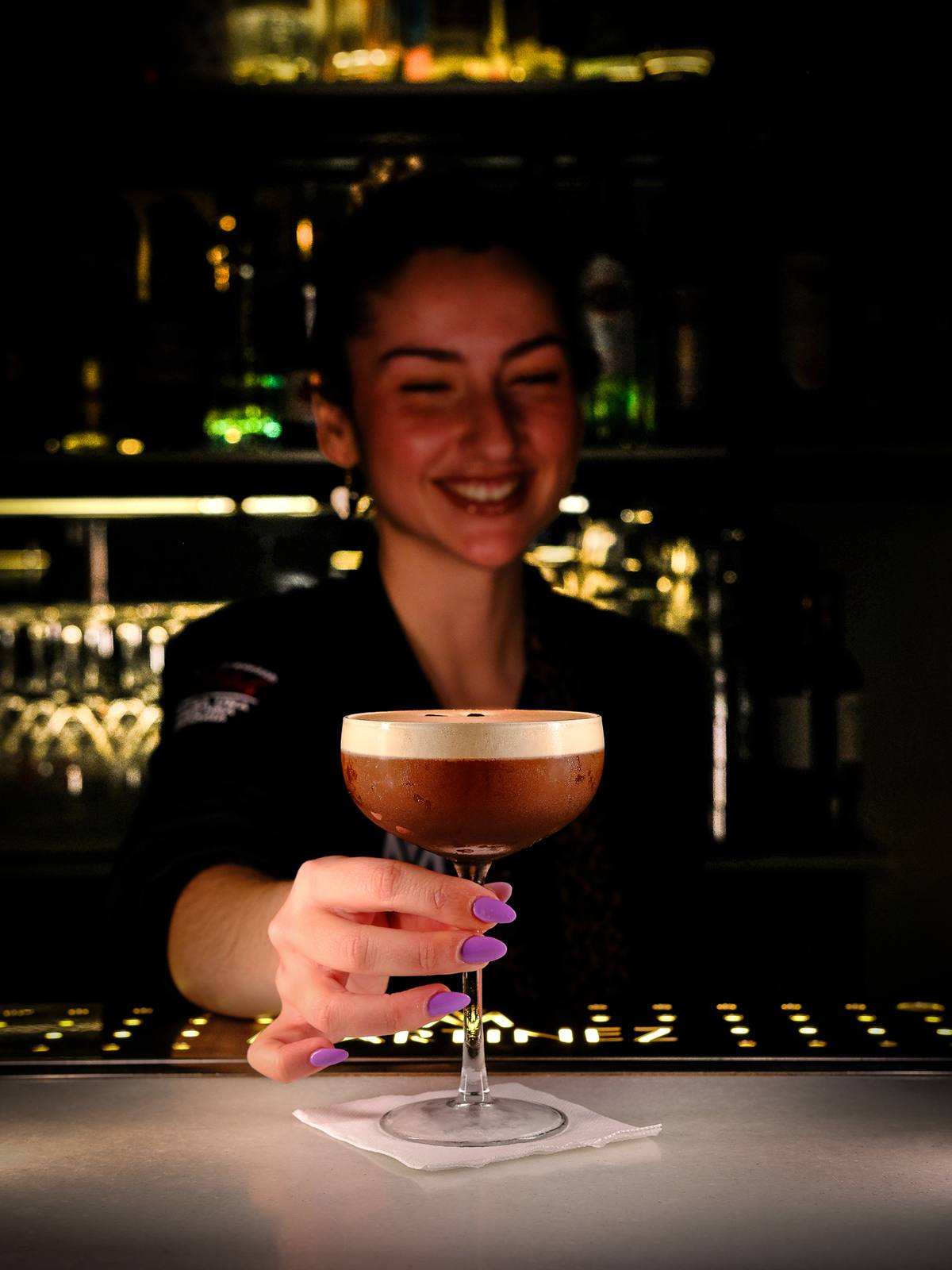 Camarera sirviendo un Espresso Martini en la barra de Martínez Bar