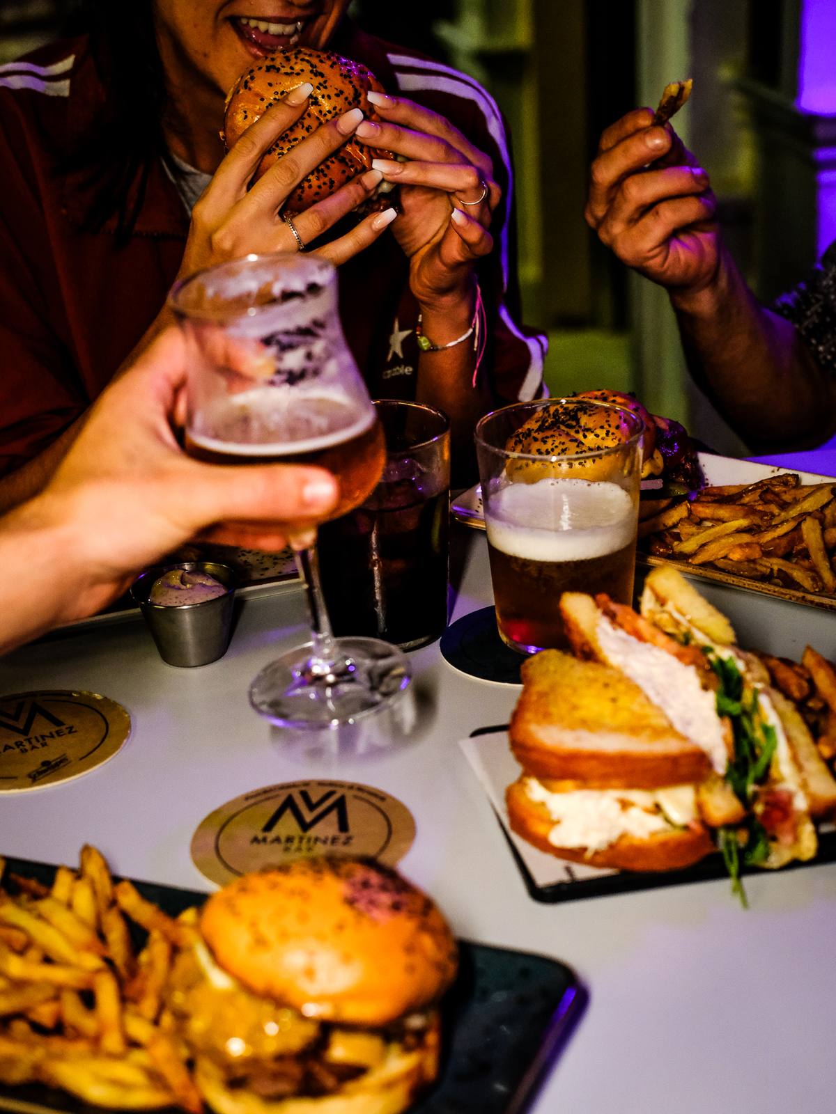 Mesa con burgers, patatas y cervezas entre amigos