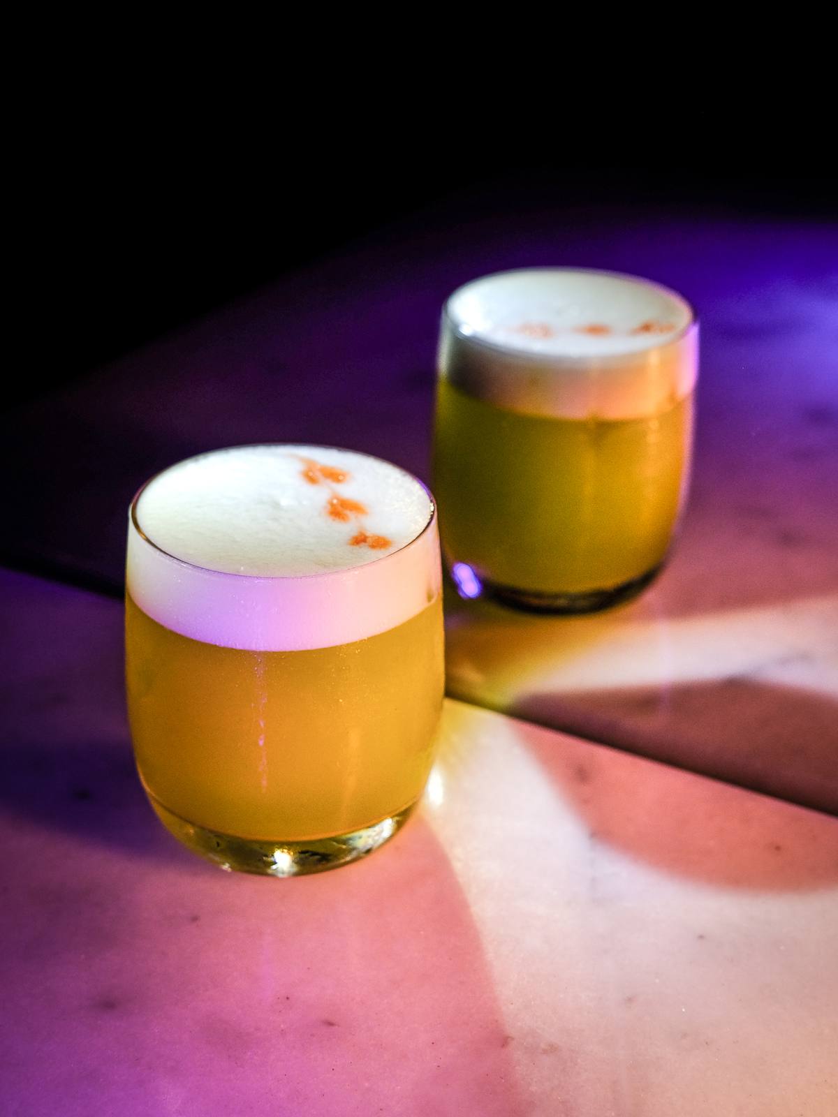 Dos cócteles sour con espuma sobre la barra